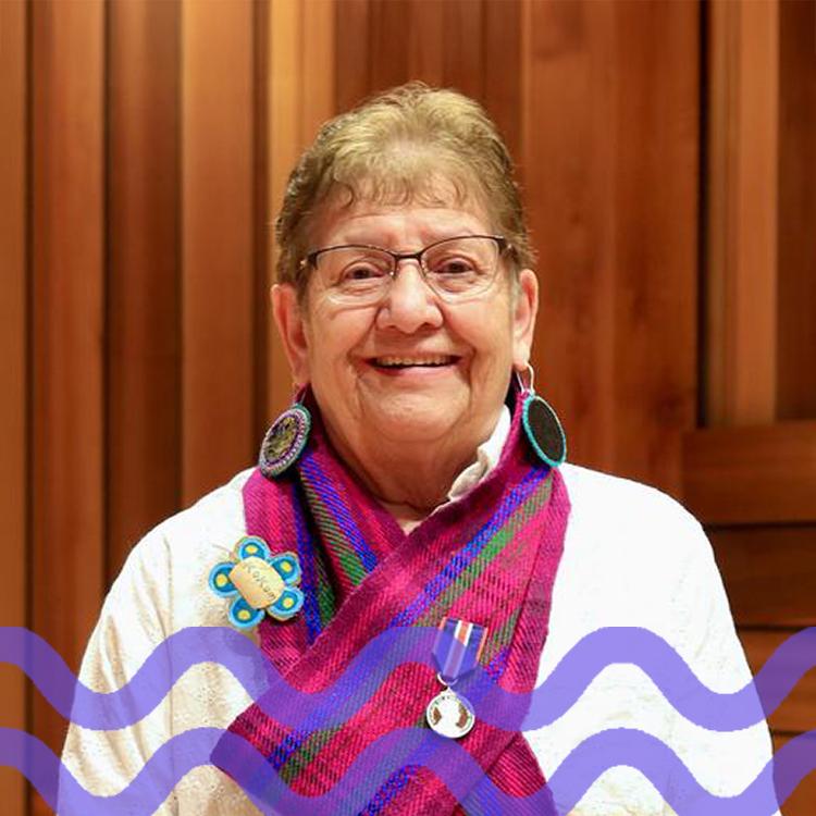 Woman with glasses and a pink and blue scarf with a purple wave pattern