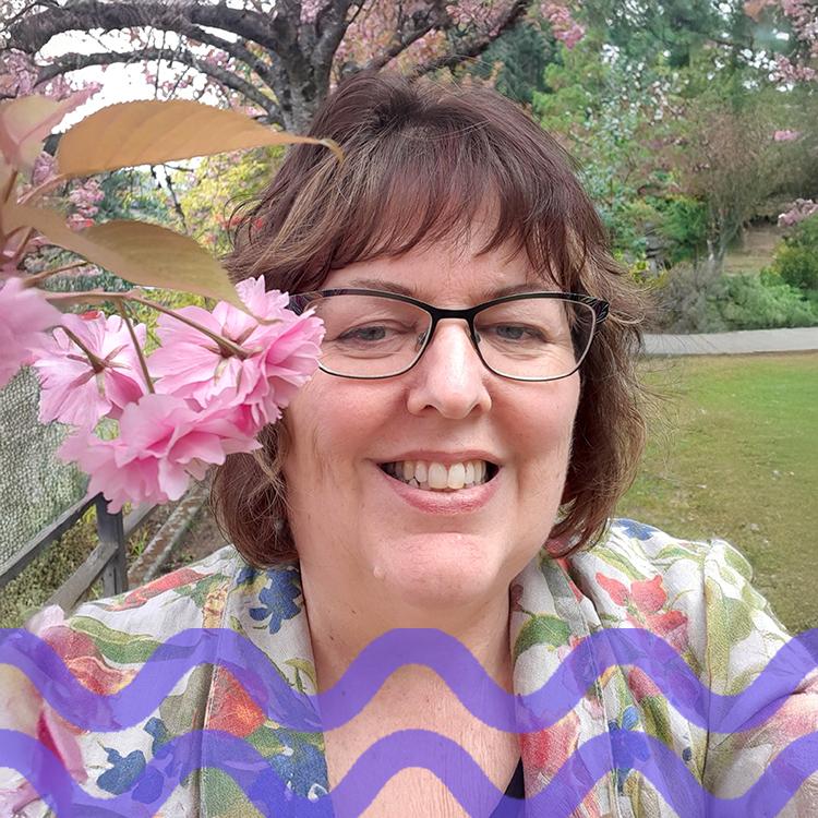 Smiling woman with glasses and brown hair with a purple wave pattern