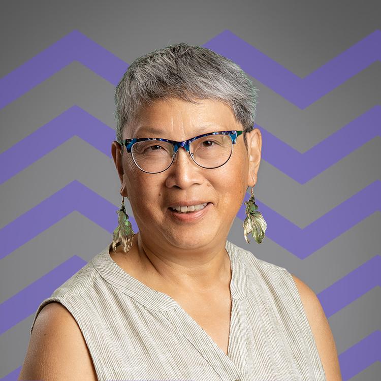 Smiling woman with short hair and glasses in front of a purple mountain pattern